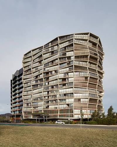 Ovolo Nishi, Canberra — the Nishi building's distinctive wavy timber-and-glass facade beside Lake Burley Griffin.