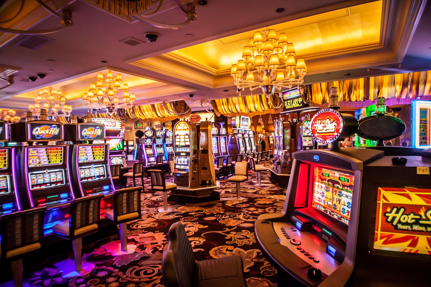 Grand illuminated casino resort facade at night reflected in water, warm gold and amber lighting.