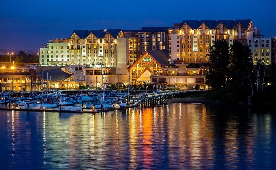 River Rock Casino Resort — waterfront resort with its own marina at twilight, yachts moored, warm interior glow, mountains beyond.