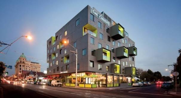 The Cullen, Prahran — bold pop-art hotel exterior at dusk with lime-green balconies and illuminated ground-floor dining.