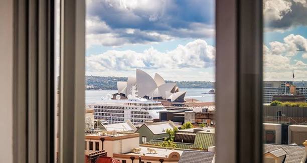 YHA Sydney Harbour pod room — a compact private cabin with harbour-bridge glimpse, timber bunk and porthole styling.